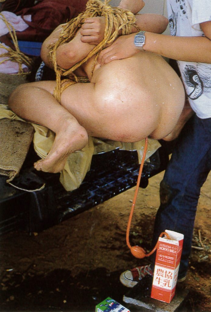 野外露出で牛乳浣腸される女のSM画像。